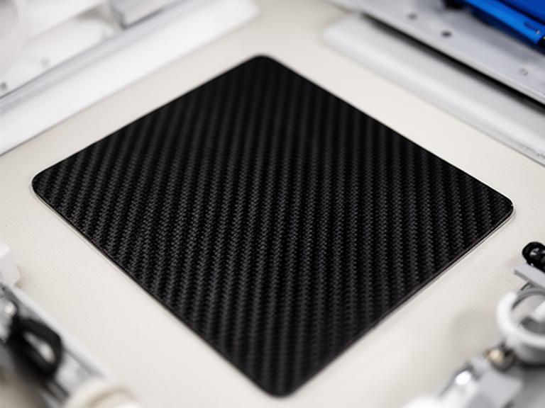 Panel aeronáutico de carbono sobre superficie clara con controles de calidad alrededor